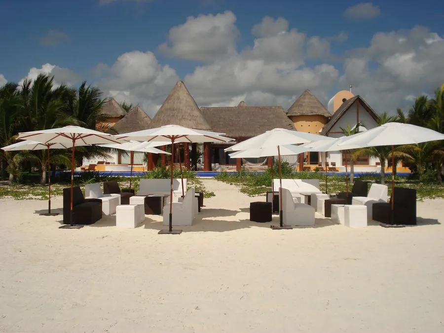 Salas lounge y sombrillas frente a palapas